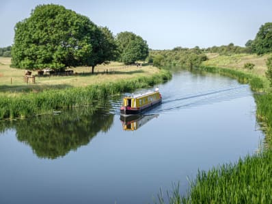 barge boat traveling down the river between green fields