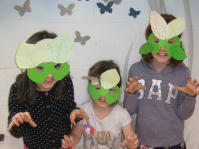 three children wearing natural art masks