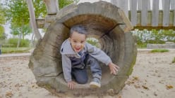 young boy climbing in a tunnel in a park playground
