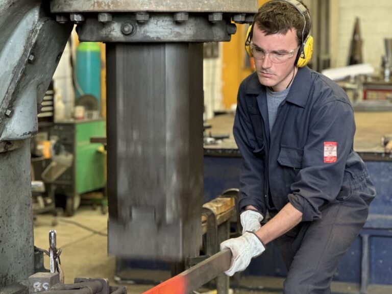 welder in a workshop welding a strip of metal