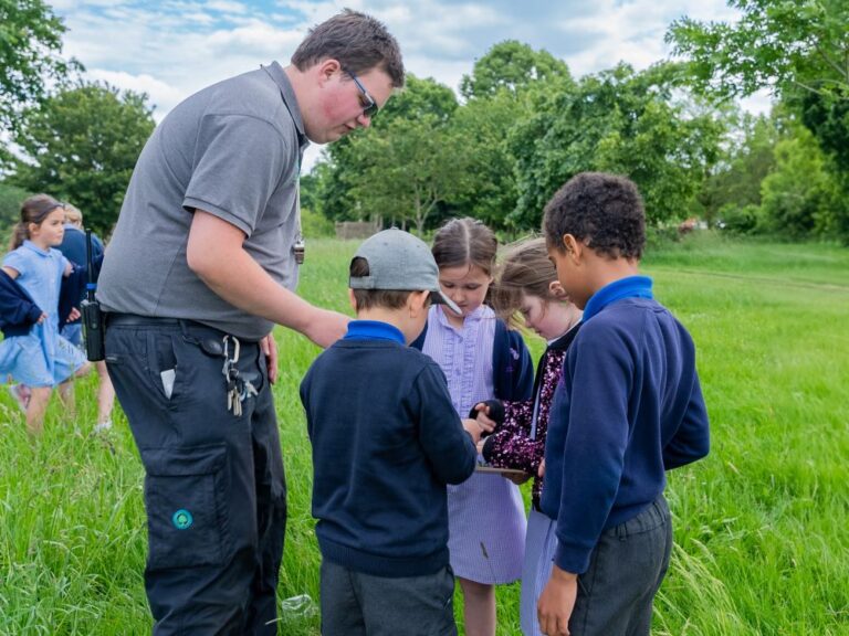 group of primary school pupils with an outdoor learning instructor on a green field