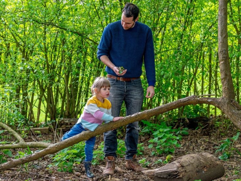 Dad and young daughter in the woods playing by the trees