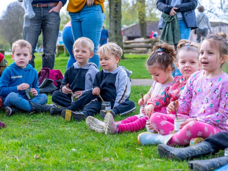 Group of toddlers sitting in a row outside in the spring