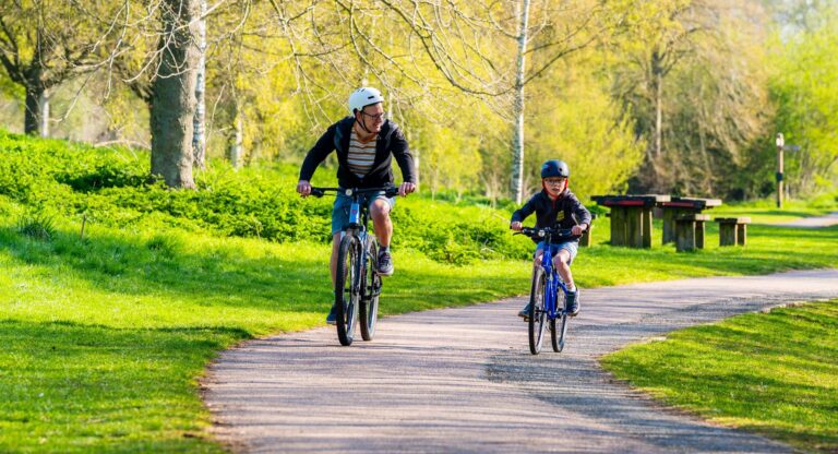 Father and son cycling along a path in a country park