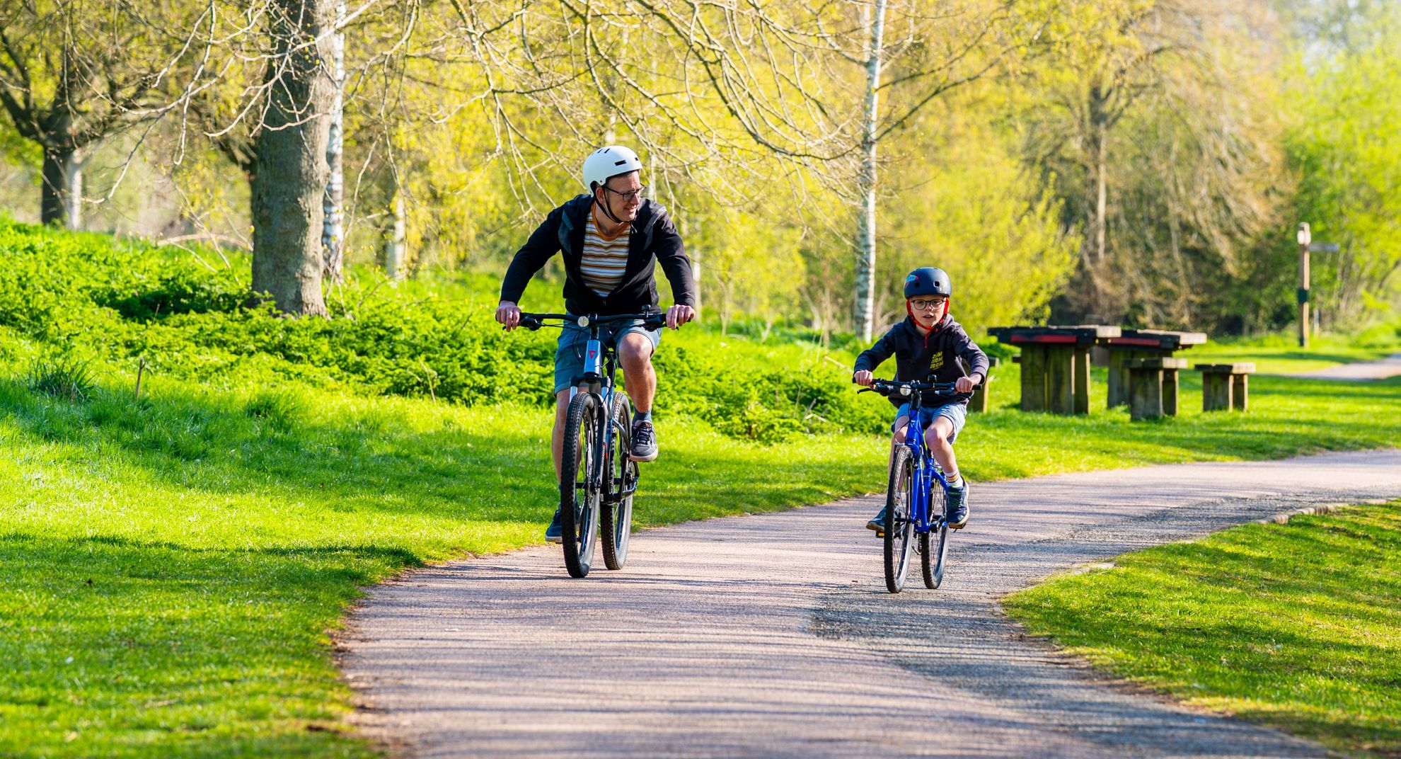 Father and son cycling along a path in a country park