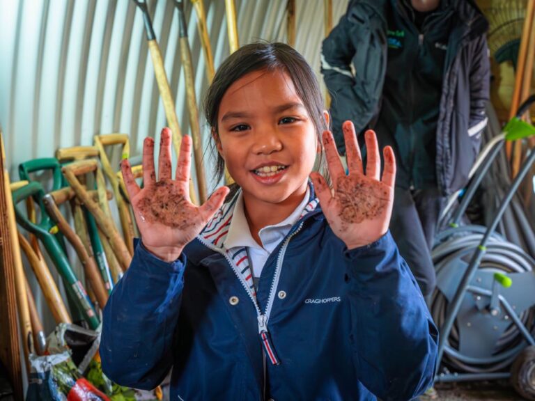 young school girl showing her mud spattered hands on a school visit to Ferry Meadows