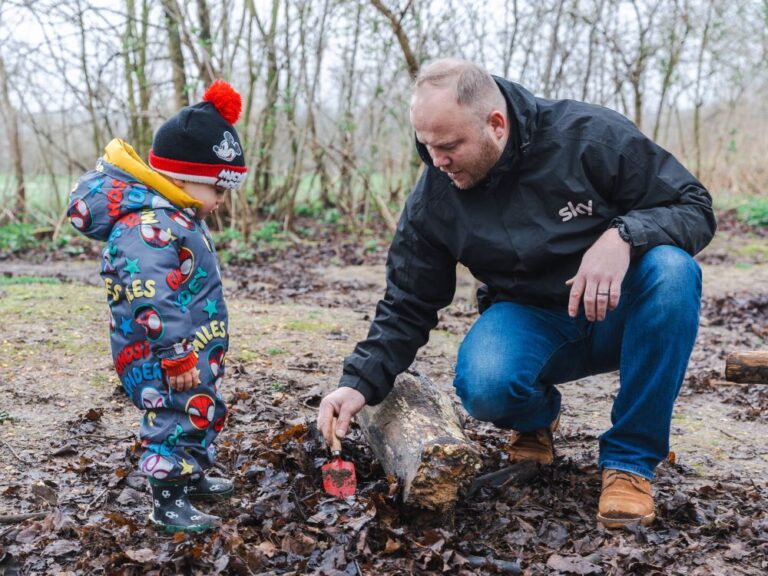 Father and toddler son outside playing in the mud in the winter woods