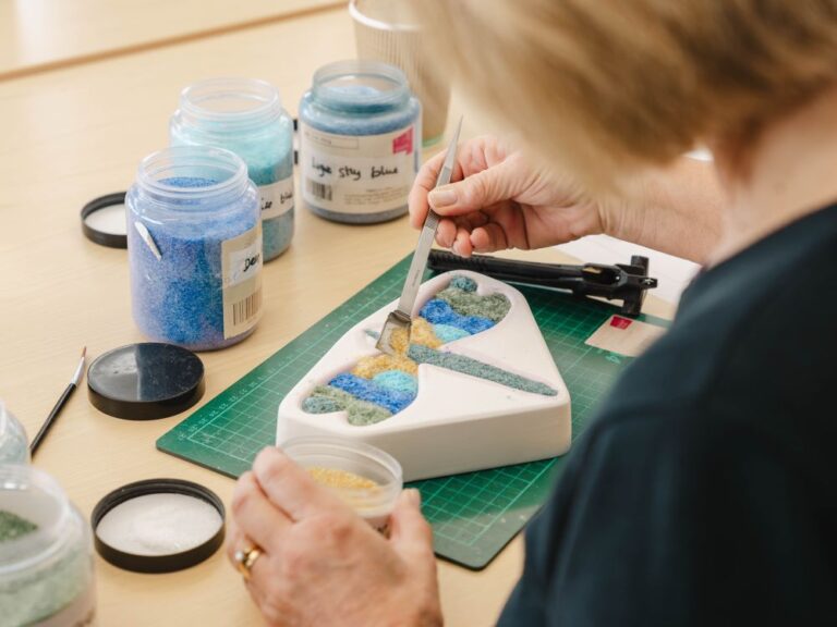 woman making a glass dragonfly in a craft workshop