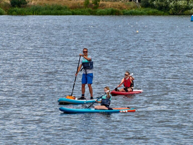 Father and two children enjoying paddleboarding on a lake