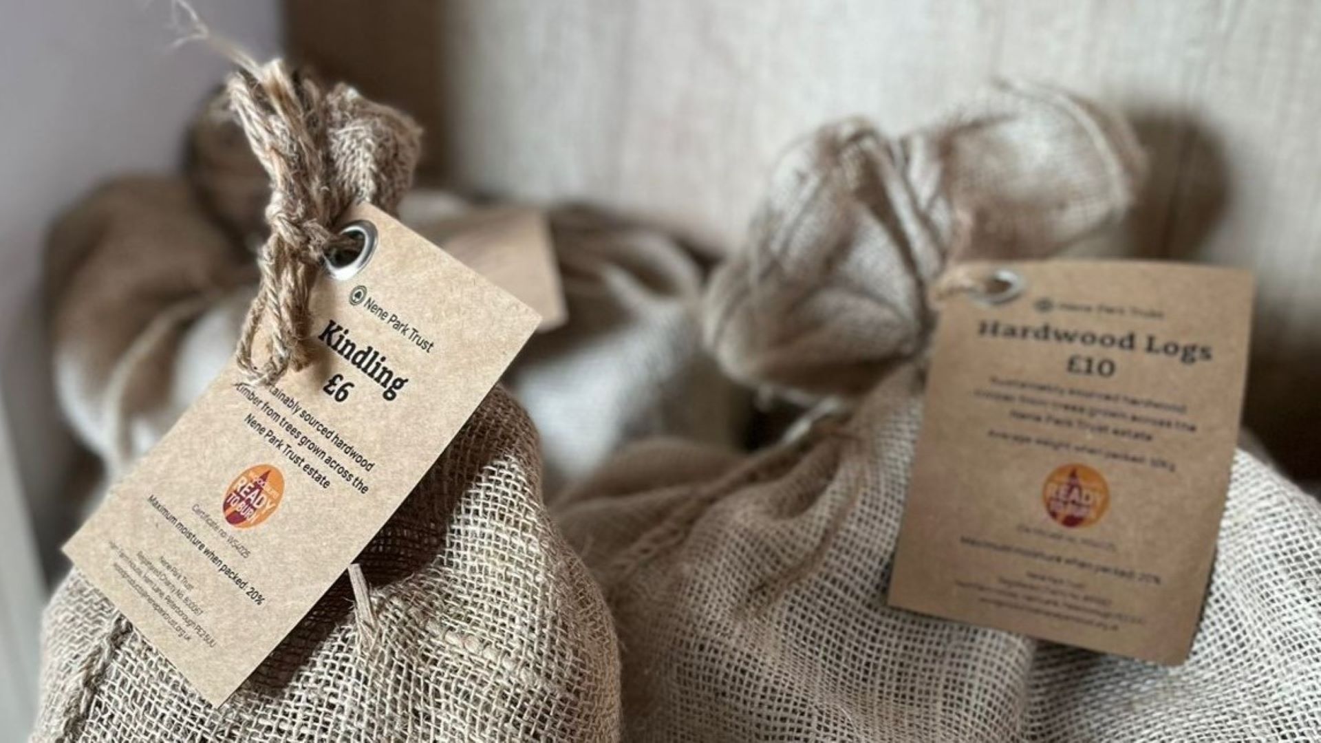 Two bags of firewood in hessian sacks with the firewood tag around the top.