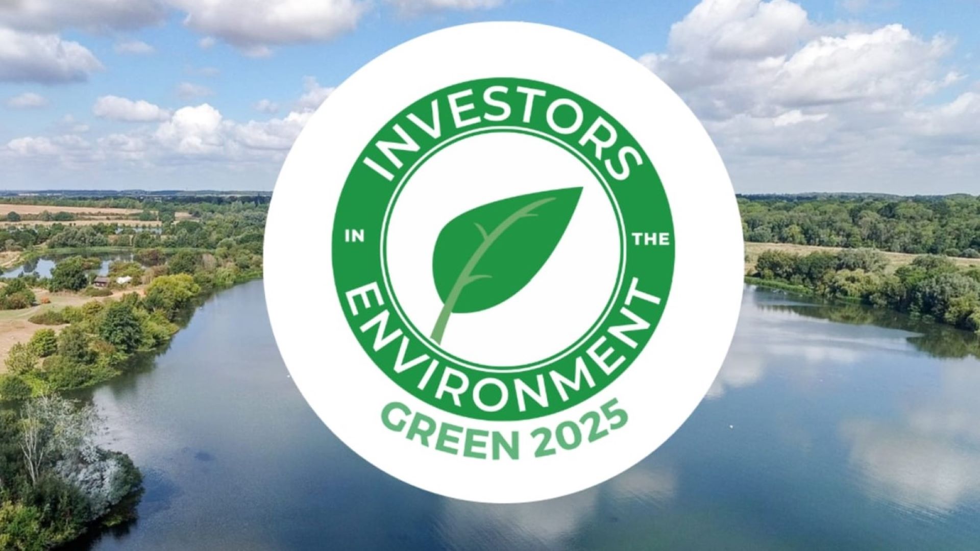 Investors in the Environment white and green logo overlapping a lake drone image from Ferry Meadows