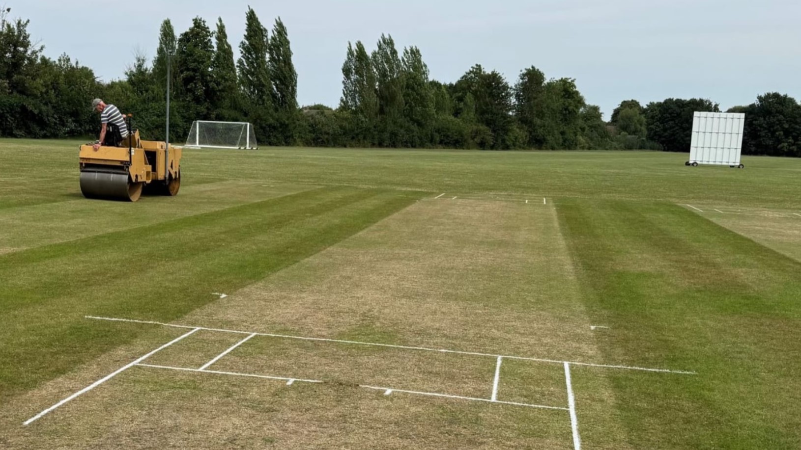 man on a yellow rotator maintaining a sports pitch
