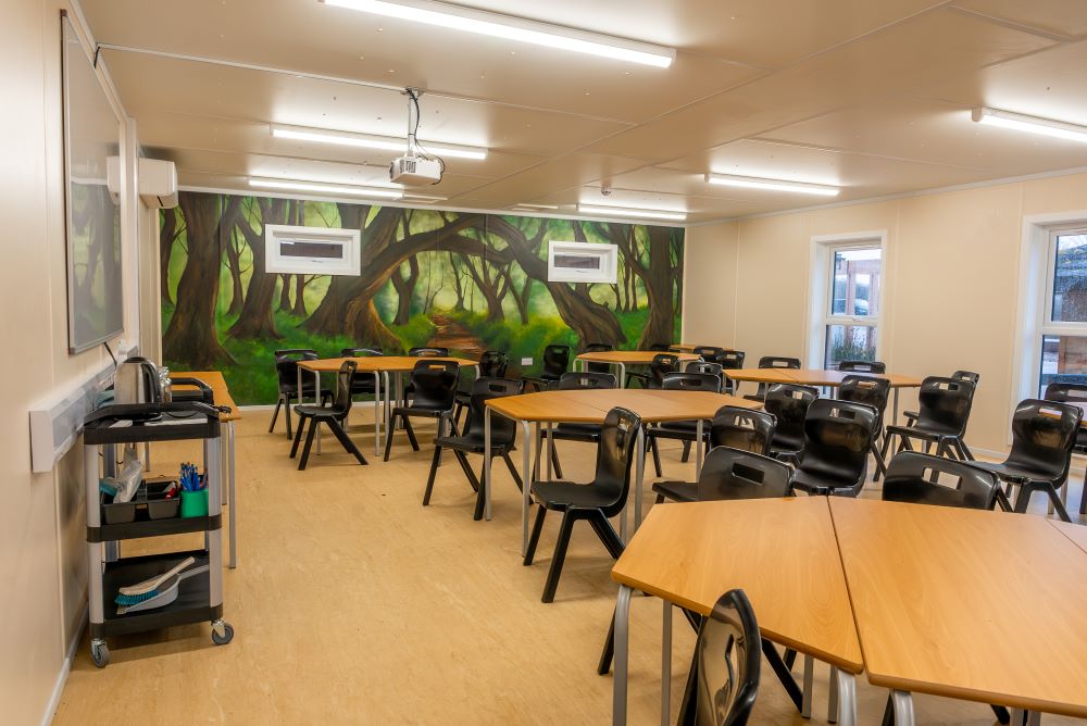 Internal view of The Sett classroom at Ferry Meadows with classroom style layout and a colourful nature mural on the back wall