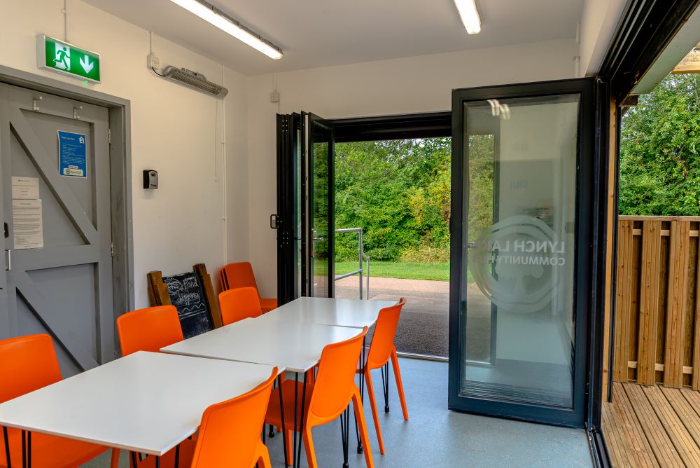 Inside Lynch Lake Community Hub with white tables and orange chairs