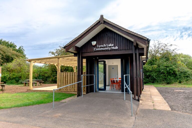 Outdoor view of a small dark brown wooden building with a wooden decking area to the left