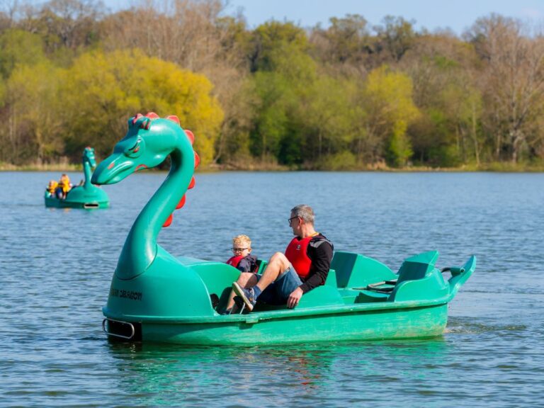 father and young son in a green dragon pedalo boat on a lake