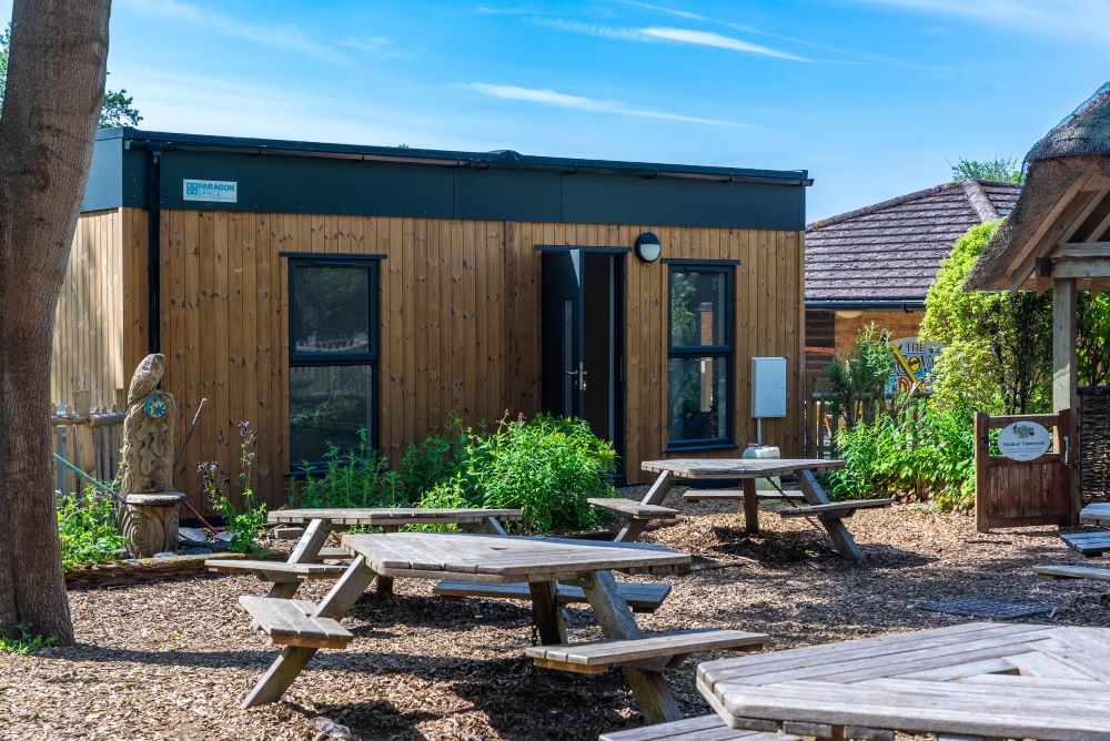 A wooden clad building behind an outdoor picnic space