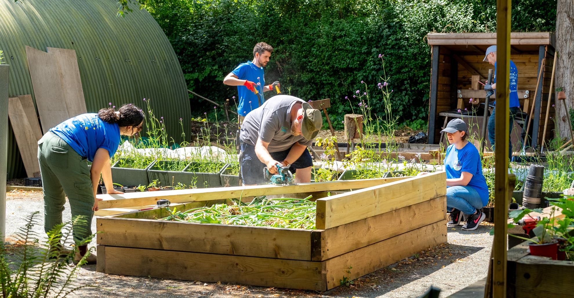 Group of young adults working in an outdoor nusery building flower beds