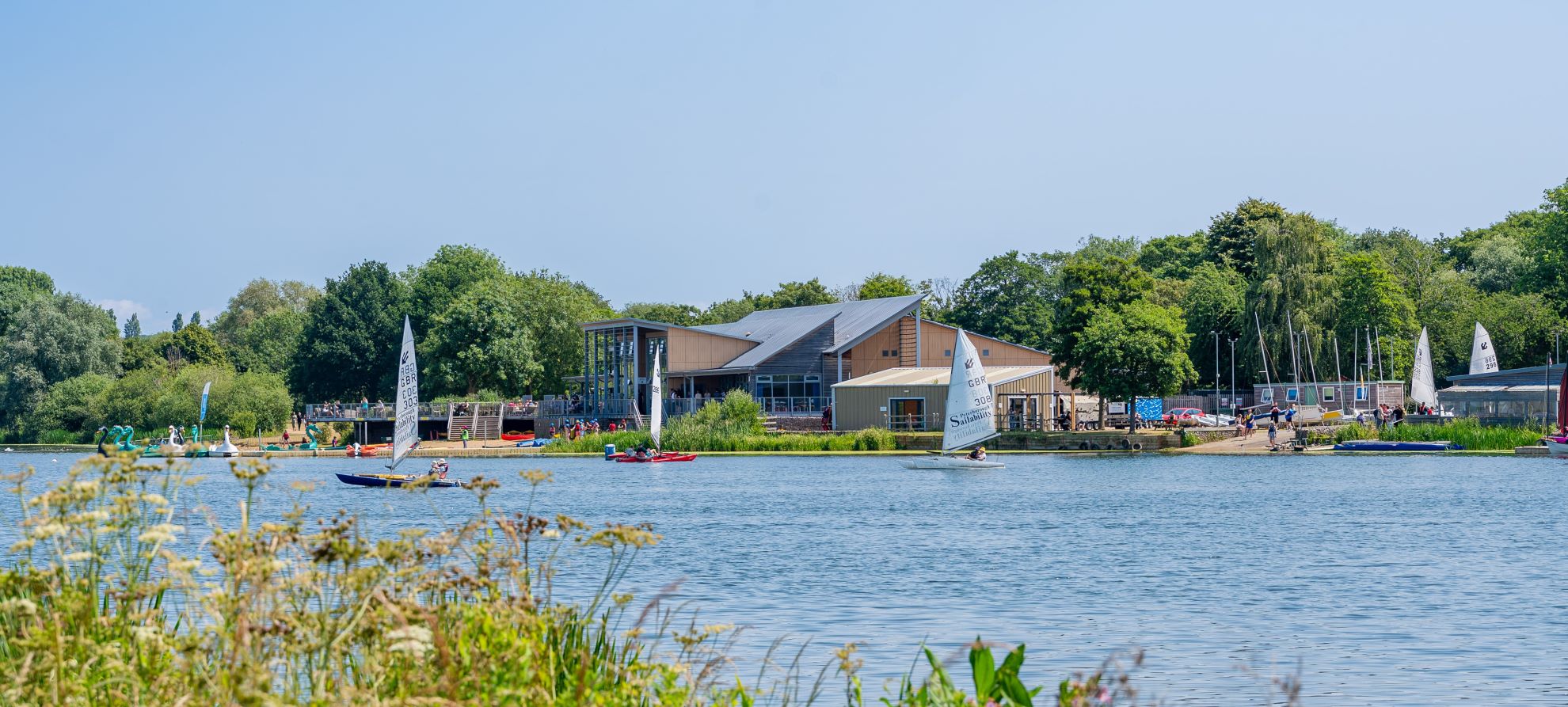 View across a large lake to a watersports and activity centre with boats on the lake
