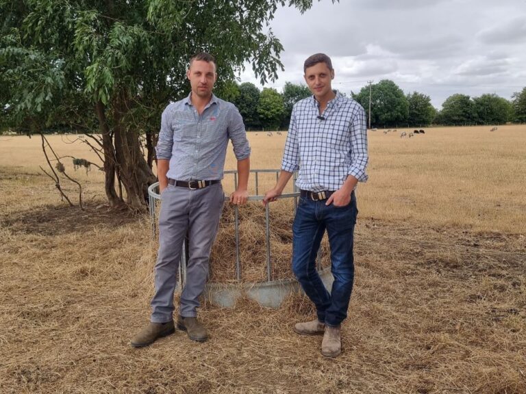 two young male farmers stood in a farming field