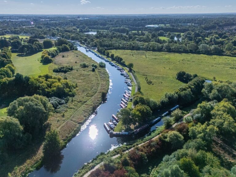 A drone image over a river surrounded by fields and green trees