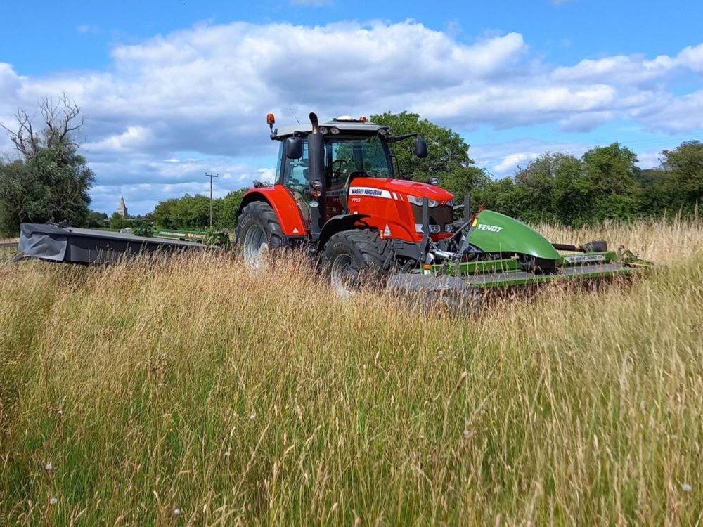 red tractor cutting hay in a farming field