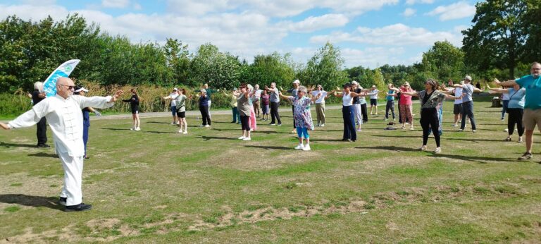 Group of people practising Tai Chi in a park.