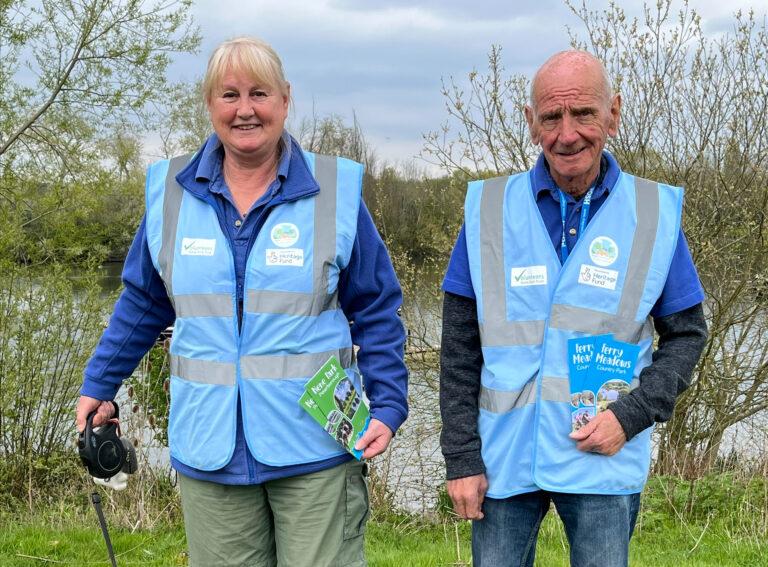A man and a woman wearing blue volunteer vests.