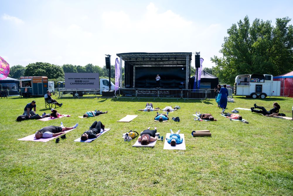 outdoor yoga taking place in front of a festival stage