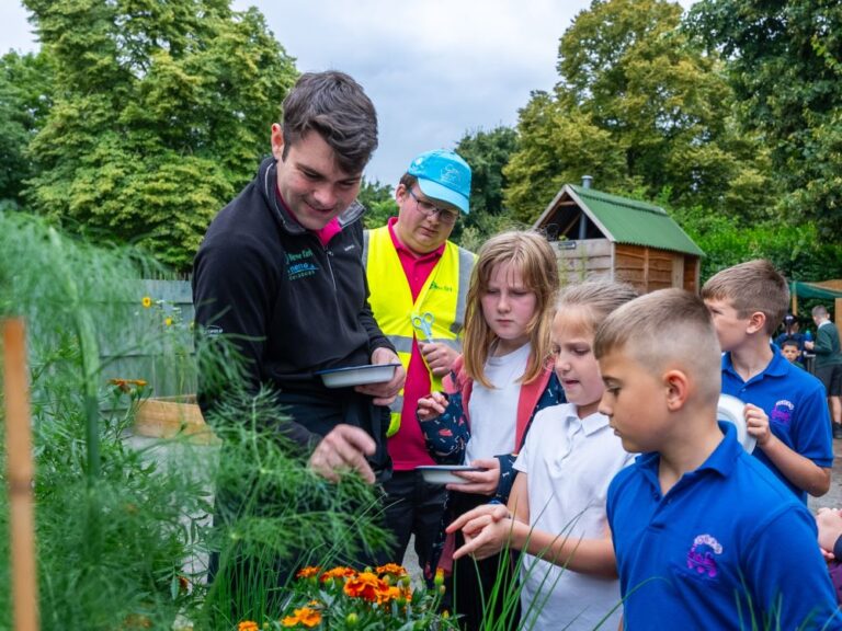 Two members of staff leading a primary school group in some outdoor learning activity