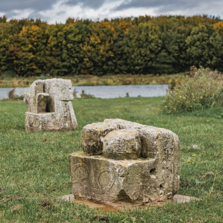 stone sculptures next to a lake