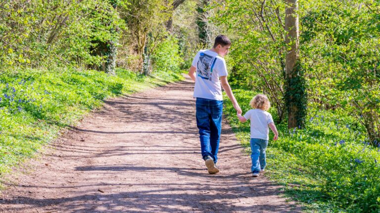 Brother and sister walking down a woodland path hand in hand