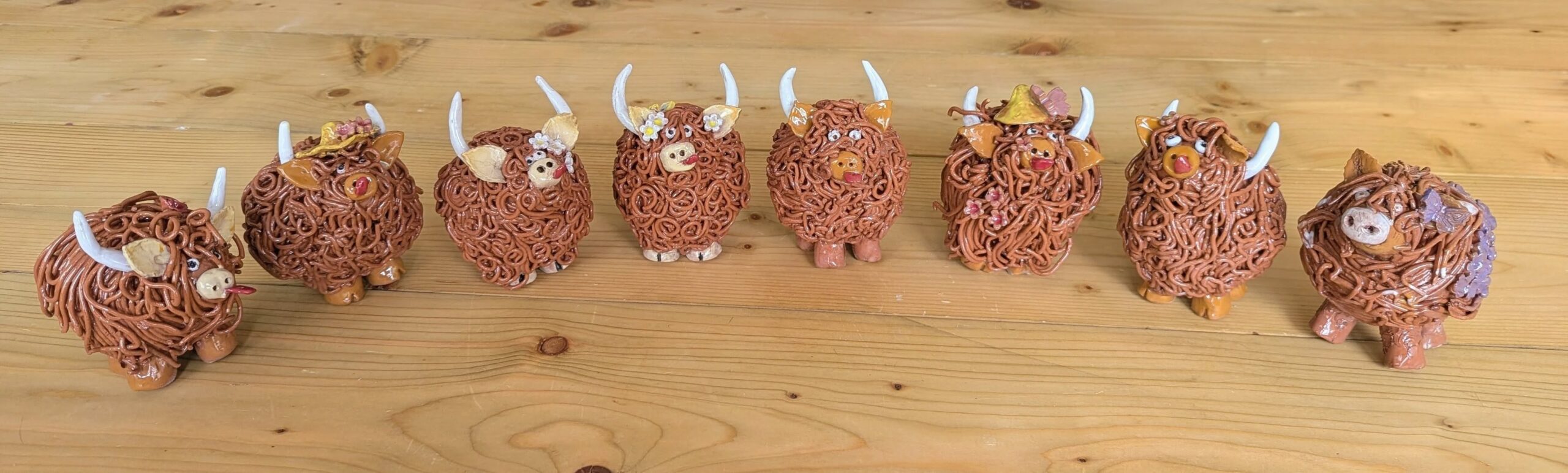 pottery highland cows lined up on a wooden desk
