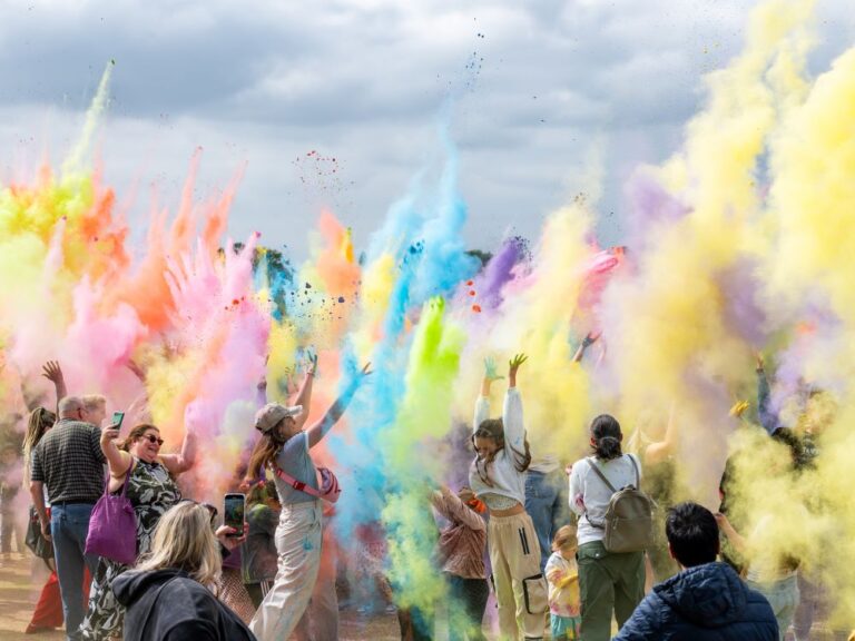 Scene showing people throwing coloured paint powder into the air as part of the Hindu festival Holi