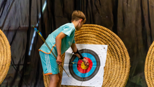 Boy taking archery arrows out of a archery target