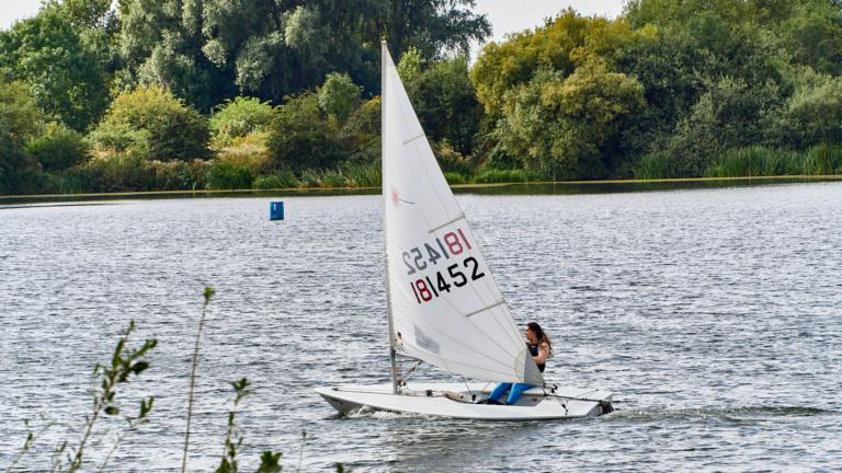 Female sailer in a small white sailing boat on a lake