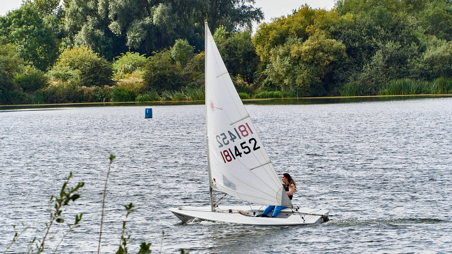 Female sailer in a small white sailing boat on a lake