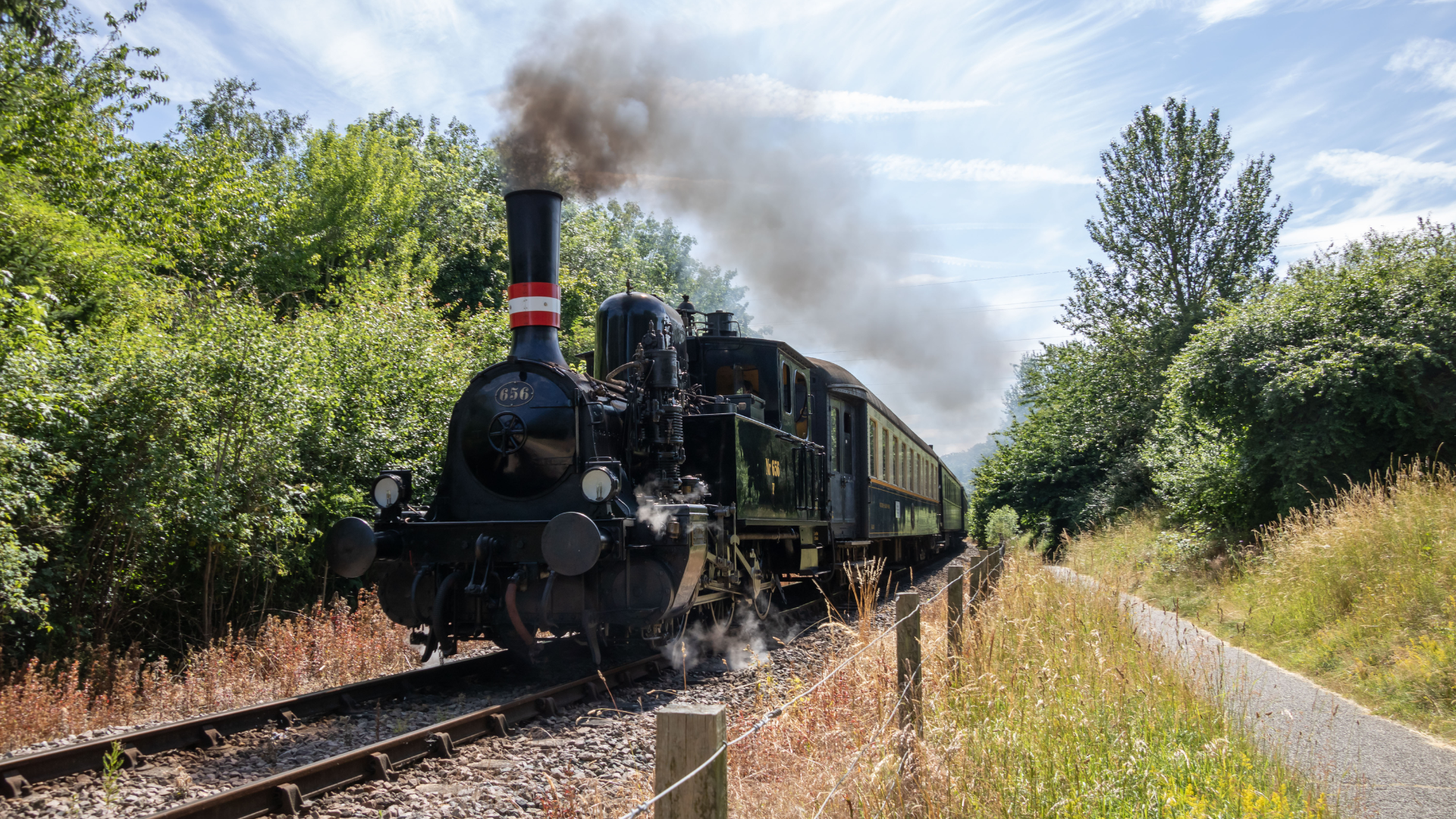 a black steam train racing through the countryside