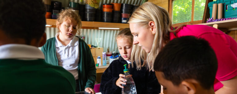 Group of schools children with a teacher in a gardening potting shed.