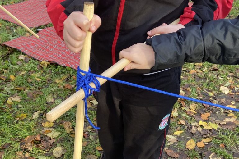 child holding two wooden poles with blue string knotted around