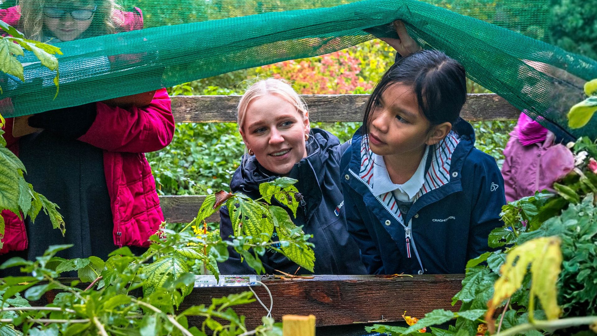 school girl and outdoor activity instructor working in a nursery garden