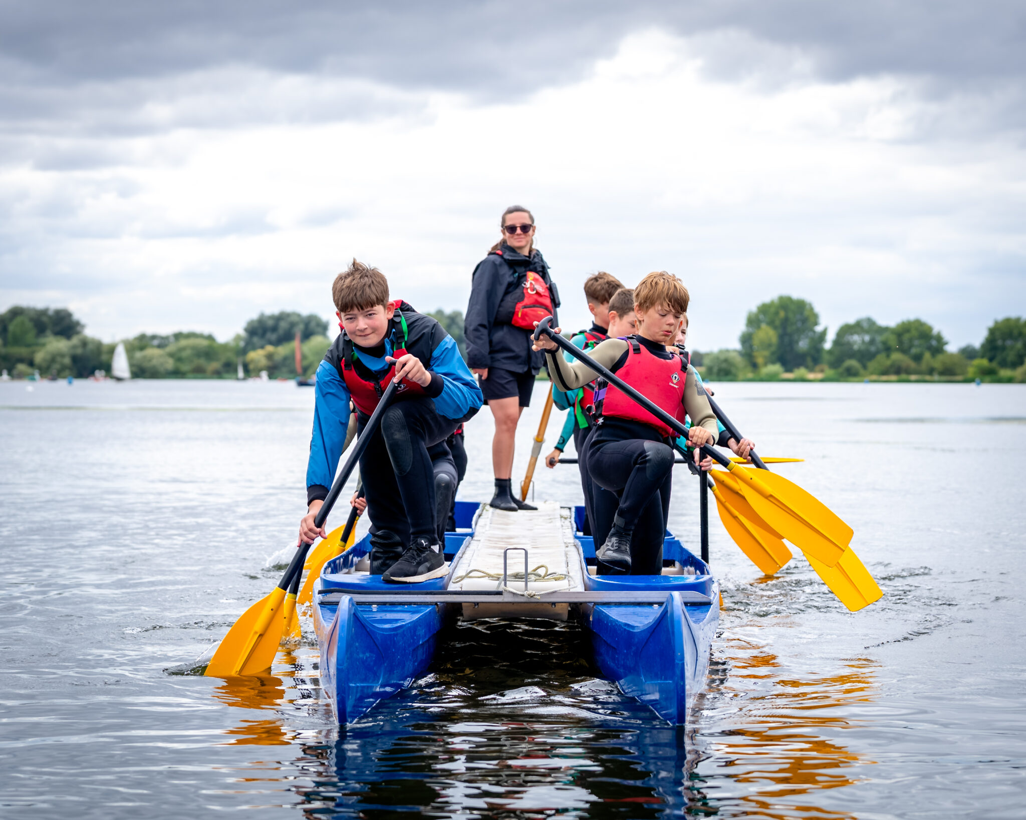 Group of children on a double kayak on a lake.