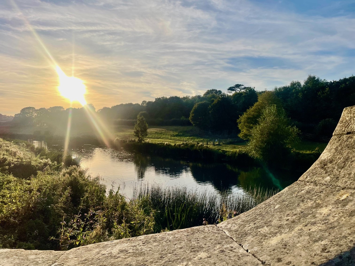 View of a river at sunset taken from a stone bridge.