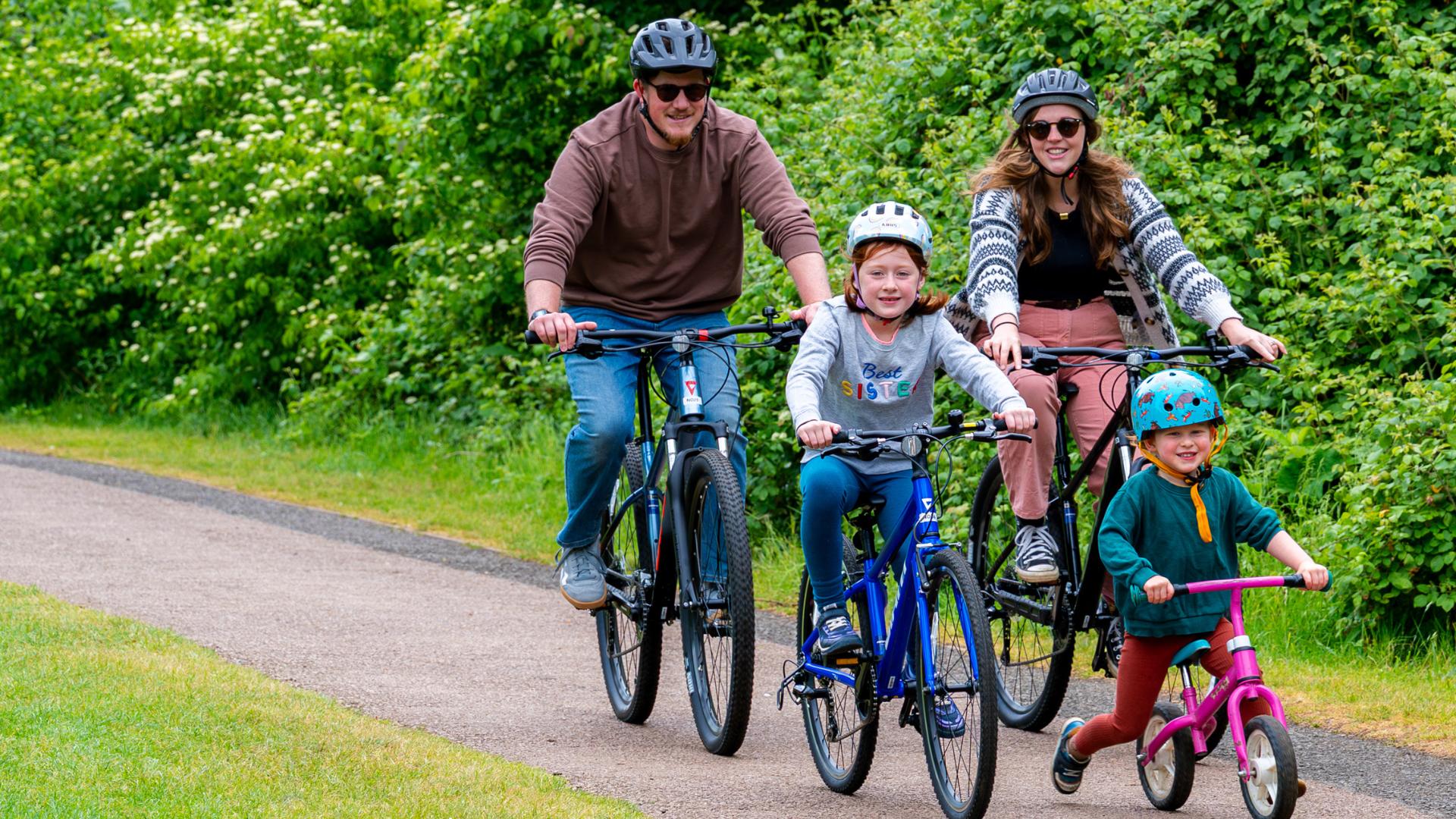 Family cycling on a path in a park.