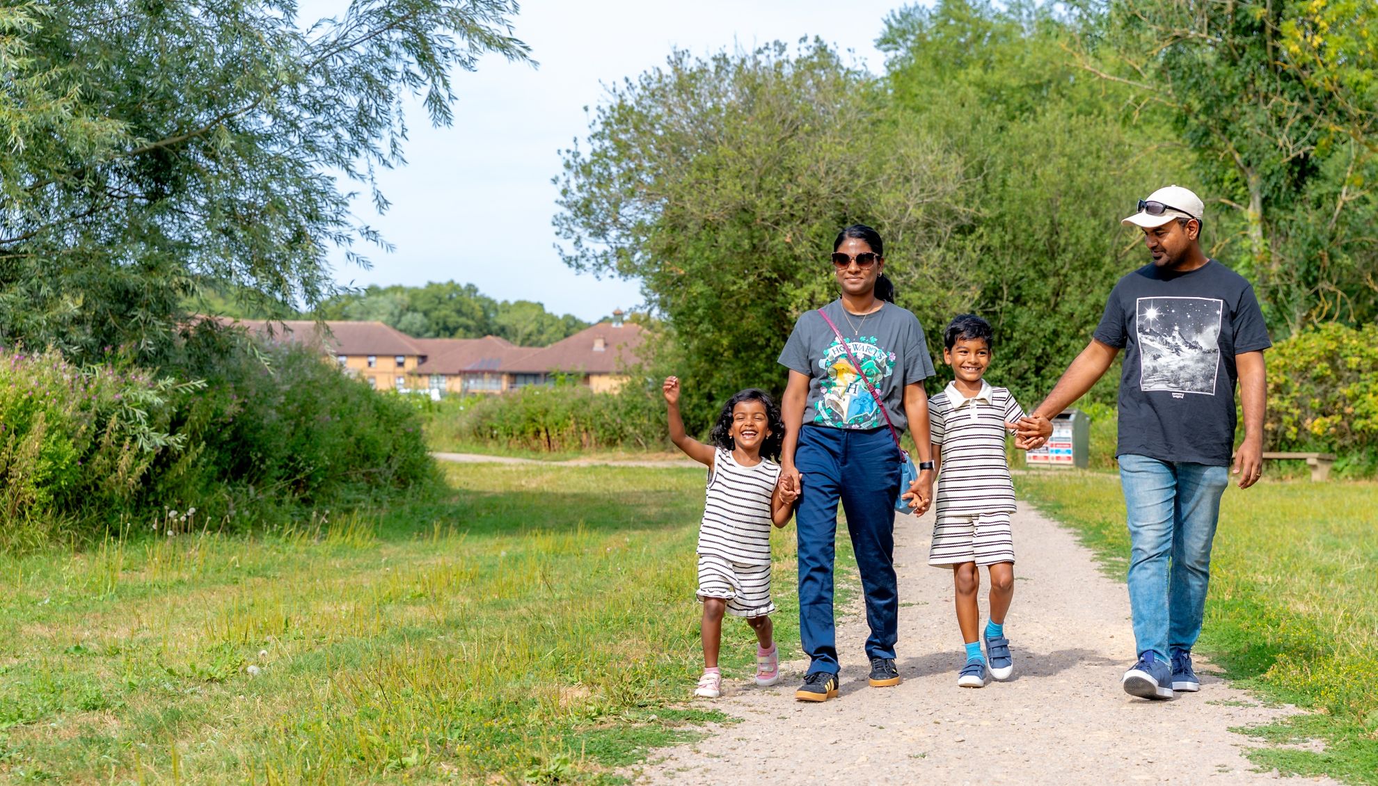 Mum, dad and young son and daughter walking on a path through a country park