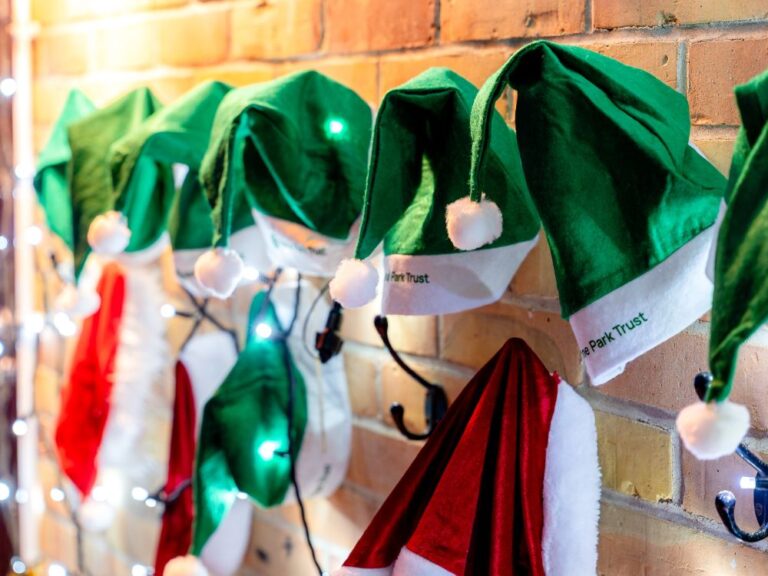 row of green elf christmas hats on a coat rack