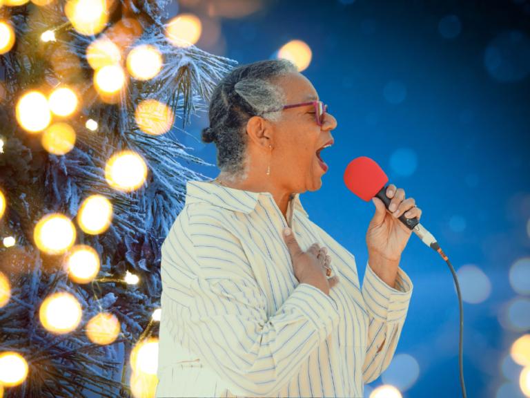 Female singer with a red microphone infront of a festive backdrop